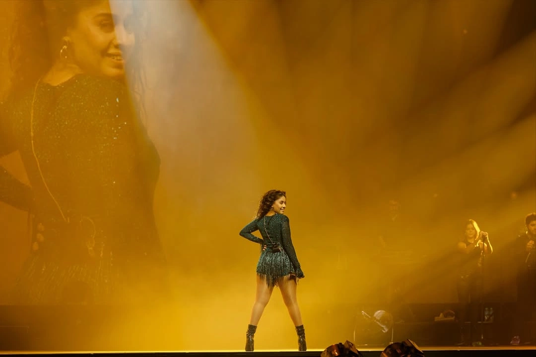 Sunidhi Chauhan performing on stadium stage with golden LED visuals — TKC Talent booking